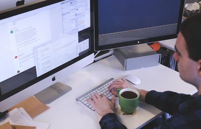 A person working at a desktop computer with a dashboard open on the monitor